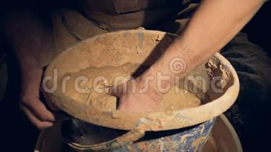 一个陶工开始在桶里混合粘土。